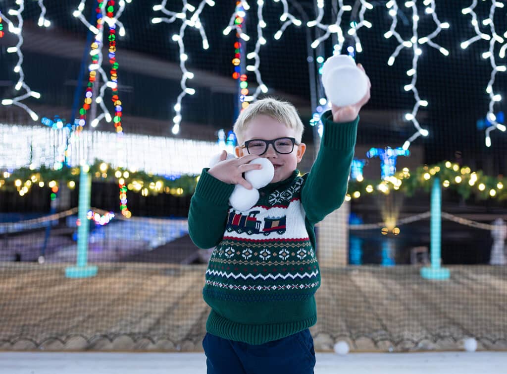Little Boy holding snowballs at Winterfest in the Snow Ball Zone